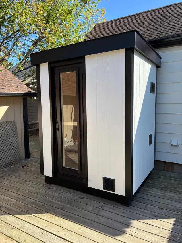 White sauna with black trim on a wooden deck