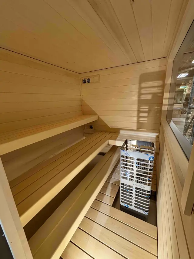 L-shaped aspen benches beside the heater in a 92" x 76" sauna