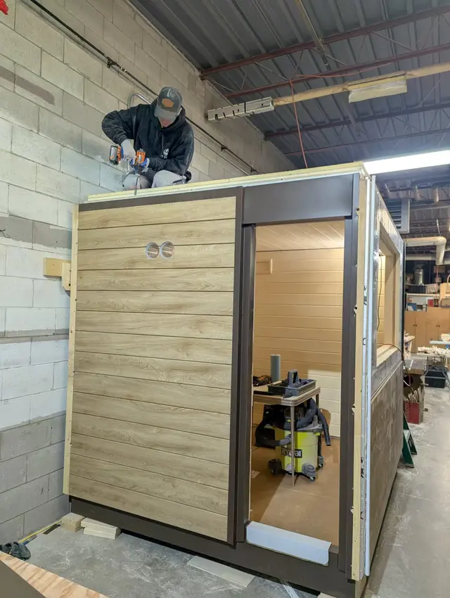 Attaching the ceiling to a sauna with Sunbleached Oak Chamclad walls and espresso aluminum trim, in the shop