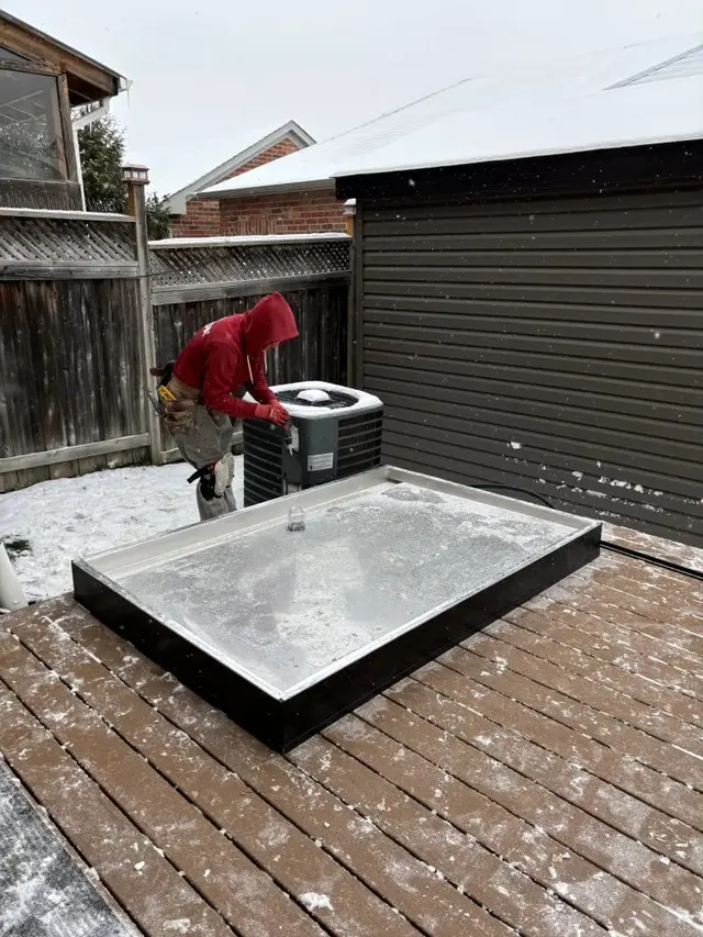 Installer beside a sauna floor base on a snowy deck