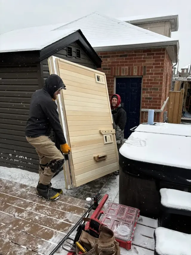 Installer carrying an aspen wall panel onto a snowy patio