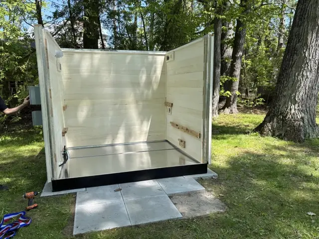 Aspen wall panels standing on a sauna base on a lawn