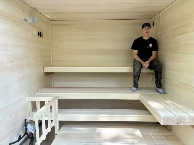 Person sitting on an L-shaped aspen bench inside a sauna