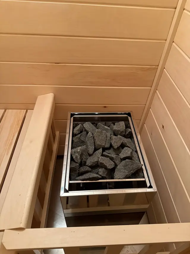 Heater with sauna stones behind an aspen railing