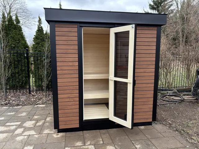 Woodgrain sauna with the door open on a paver patio
