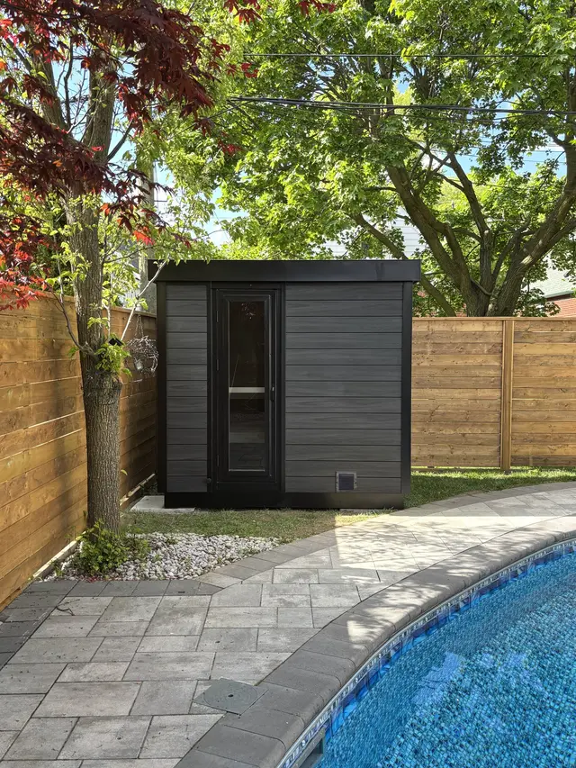 Black sauna beside a paver patio and a pool