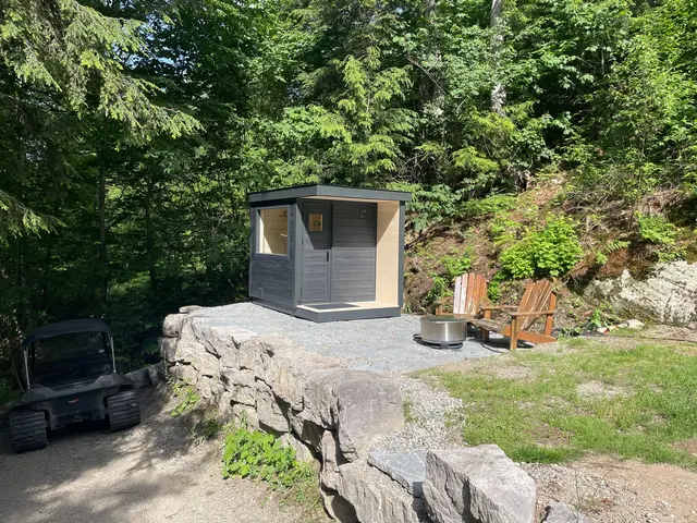 Grey sauna on a stone terrace in a wooded yard