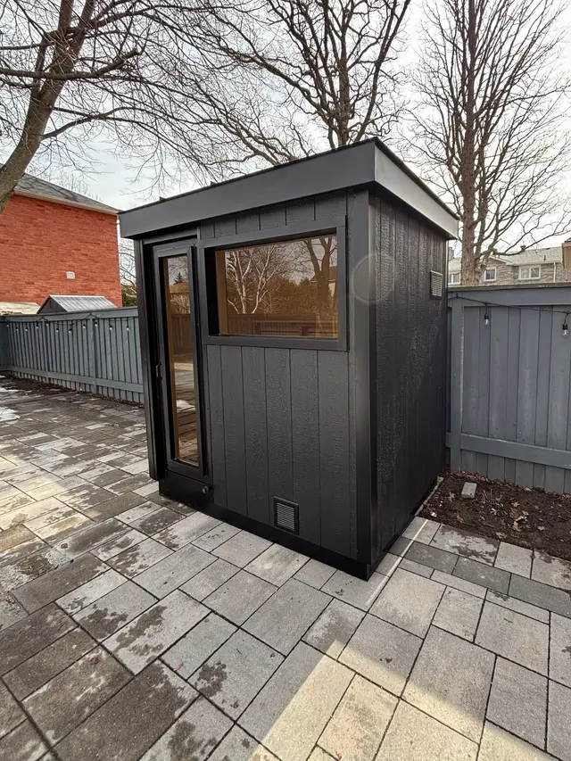 Black sauna with a front window on a paver patio