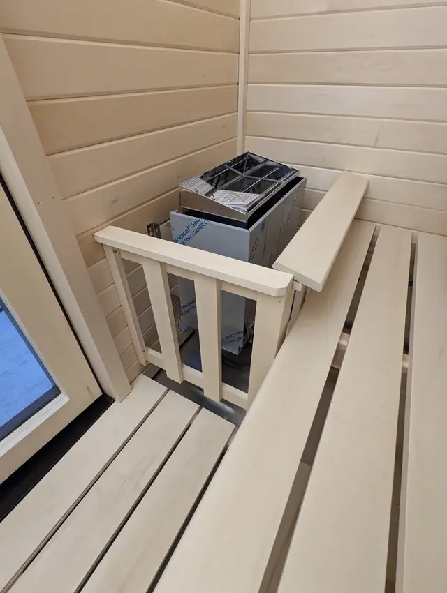 Heater and aspen railing inside a sauna with a window