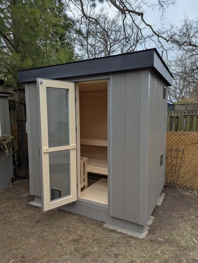 Grey sauna with the glass door open to the benches