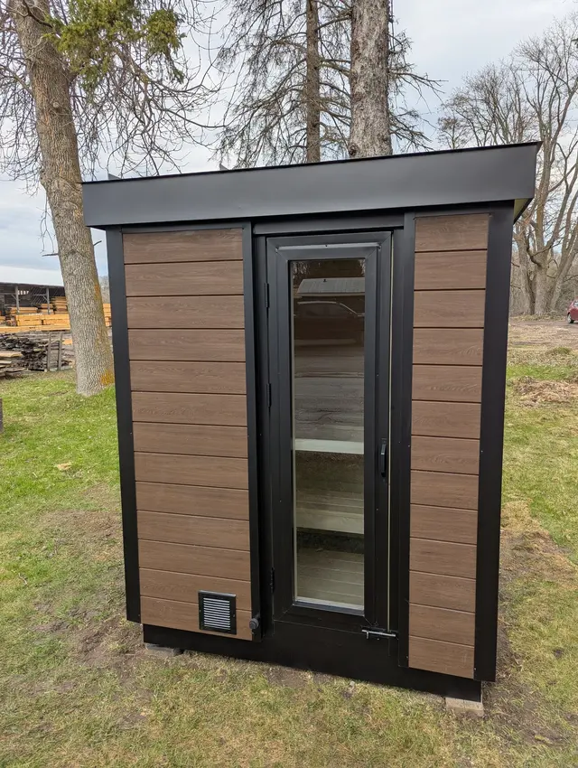Woodgrain sauna with a black glass door on a lawn