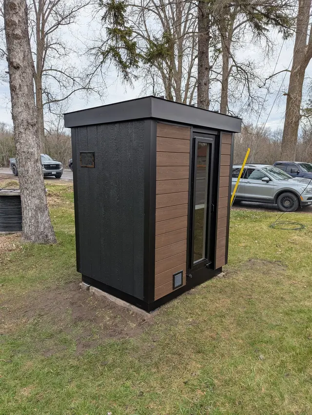 Sauna with black and woodgrain cladding on a lawn