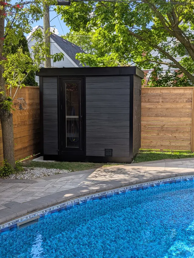 Black sauna with a glass door beside a pool