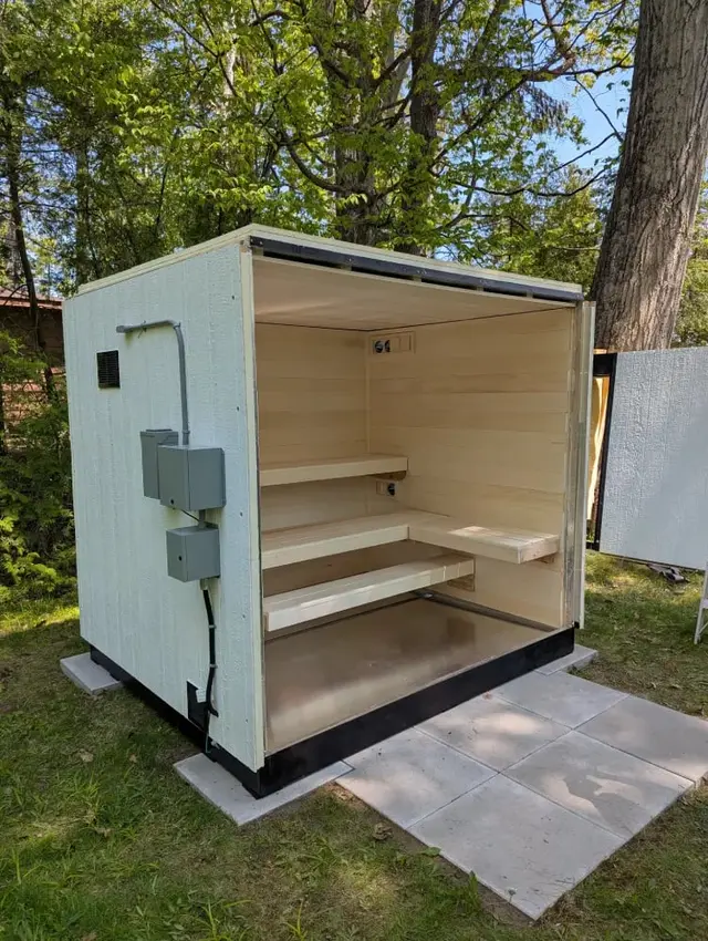 White sauna with one side open, showing the benches