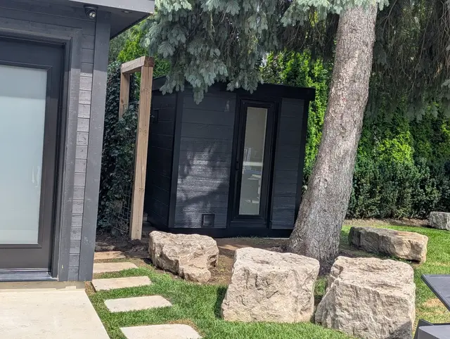 Black sauna in a garden with large boulders