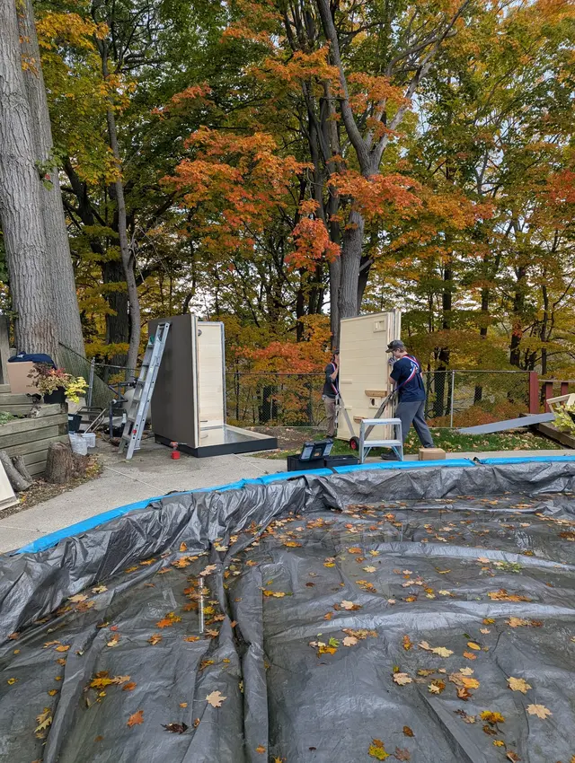 Installers assembling two saunas in an autumn backyard