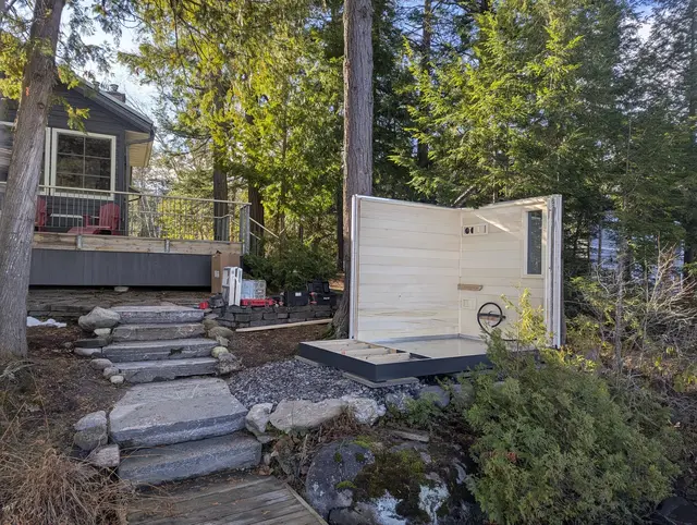 White sauna being assembled beside stone steps in a garden