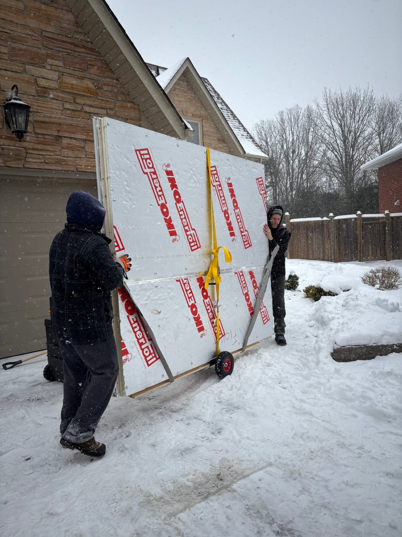 A wall panel being carried through a backyard gate