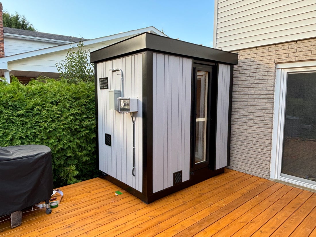 A grey-sided Ryt Sauna with its exterior electrical panel installed