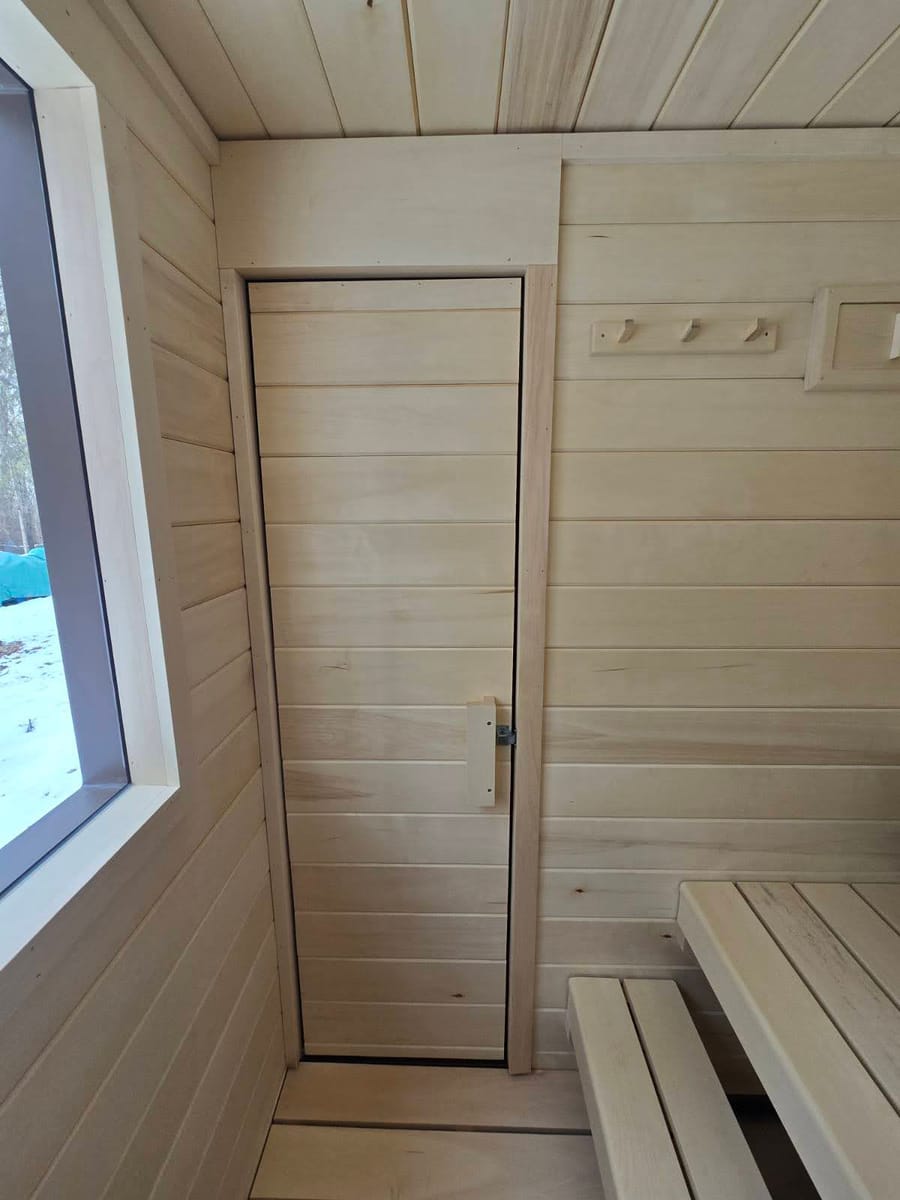 A fully insulated sauna door photographed from inside, with aspen interior walls.